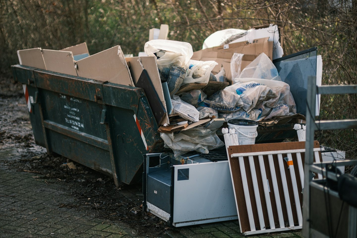 A large dumpster overflowing with construction debris and household waste.